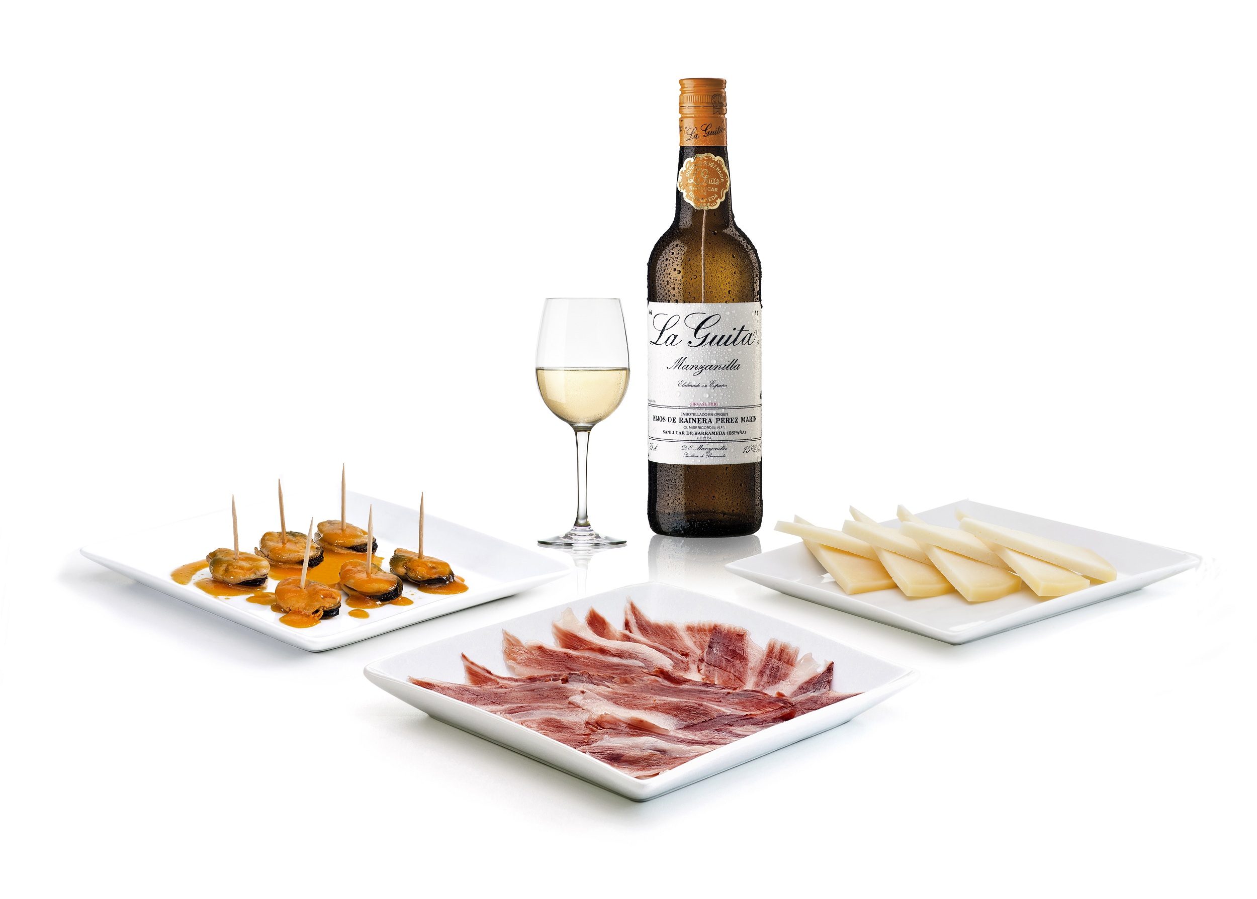 Una botella de La Guita acompañada de varios platos de picoteo.
